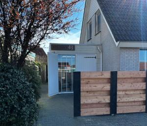 een huis met een witte garage met een houten hek bij Studio 43 in Hollum