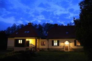 une maison éclairée la nuit dans la cour dans l'établissement Leśniczówka Agroturystyka Gabriela Pieczka, à Tuchola