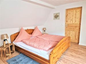 a bedroom with a wooden bed with pink pillows at modernes Landhaus Charlie - Nähe Halle, 4 Zimmer in Petersberg