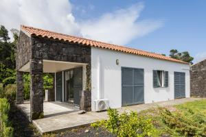 a white house with a stone wall at Villa 4 Seasons in São Roque do Pico