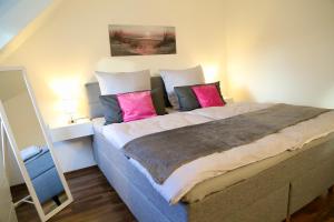 1 dormitorio con 1 cama grande con almohadas rosas en Vaubanstudio historischer Soutyhof, en Saarlouis