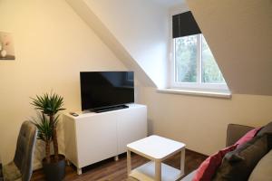 a living room with a flat screen tv on a white cabinet at Vaubanstudio historischer Soutyhof in Saarlouis