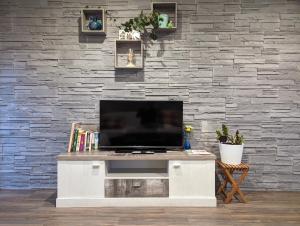 a television on a white entertainment center in front of a stone wall at Nepalaya Ferienwohnung in Pegnitz