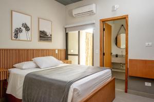 a bedroom with a large bed and a bathroom at JQY Beach Flats - 950m da Praia - Garagem subterrânea - Estação de carregamento para veículos elétricos in Juquei