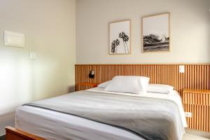 a bedroom with a large bed with three pictures on the wall at JQY Beach Flats - 950m da Praia - Garagem subterrânea - Estação de carregamento para veículos elétricos in Juquei