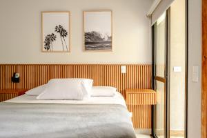 a bedroom with a bed and three pictures on the wall at JQY Beach Flats - 950m da Praia - Garagem subterrânea - Estação de carregamento para veículos elétricos in Juquei