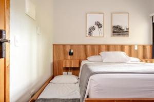 a small bedroom with a bed and twopillows at JQY Beach Flats - 950m da Praia - Garagem subterrânea - Estação de carregamento para veículos elétricos in Juquei