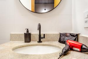 - un sèche-cheveux sur un lavabo avec miroir dans l'établissement JQY Beach Flats - Piscina - Carregador de veículos elétricos e híbridos - Garagem Subterrânea - Ar condicionado - WI-FI, à Juqueí