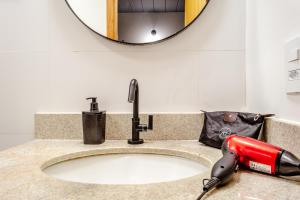 a blow dryer on a bathroom sink with a mirror at JQY Beach Flats - 950m da Praia - Garagem subterrânea - Estação de carregamento para veículos elétricos in Juquei