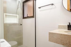 a bathroom with a shower and a toilet and a sink at JQY Beach Flats - 950m da Praia - Garagem subterrânea - Estação de carregamento para veículos elétricos in Juquei