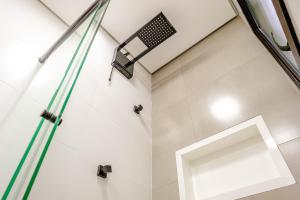 a shower with a glass door and a light in a bathroom at JQY Beach Flats - 950m da Praia - Garagem subterrânea - Estação de carregamento para veículos elétricos in Juquei