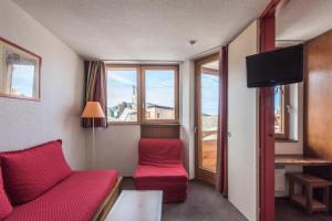a hotel room with a red couch and a window at Résidence Les Fontaines Blanches - maeva Home - Appartement 2 pièces 5 pers 91 in Avoriaz