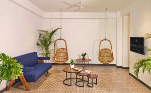 a living room with a blue couch and two tables at Minimalist Poshtel & Suites in New Delhi