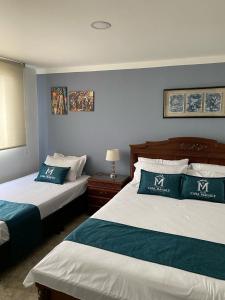 ボゴタにあるHotel Boutique Casa Magalyのホテルルーム ベッド2台 ブルーウォール