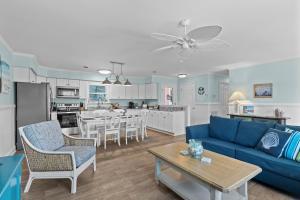 a living room and kitchen with a blue couch and a table at Colorful Emerald Isle Home Just Steps to Beach! in Emerald Isle