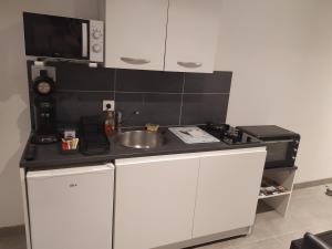 a small kitchen with a sink and a microwave at charmant gite 25m² indépendant in Alès