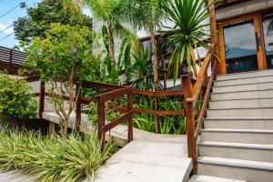 a wooden stairway leading to a house with palm trees at JQY Beach Flats - 950m da Praia - Garagem subterrânea - Estação de carregamento para veículos elétricos in Juquei