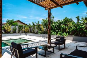 a patio with a table and chairs and a swimming pool at JQY Beach Flats - 950m da Praia - Garagem subterrânea - Estação de carregamento para veículos elétricos in Juquei