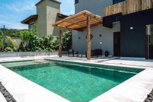a swimming pool with a pergola next to a house at JQY Beach Flats - 950m da Praia - Garagem subterrânea - Estação de carregamento para veículos elétricos in Juquei