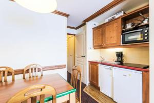 una pequeña cocina con mesa de madera y encimeras de cocina en Résidence Le Mont Soleil - maeva Home - Appartement 2 Pièces 5 Personnes - 38 en Mâcot La Plagne