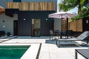 a patio with a table and umbrella next to a pool at JQY Beach Flats - 950m da Praia - Garagem subterrânea - Estação de carregamento para veículos elétricos in Juquei