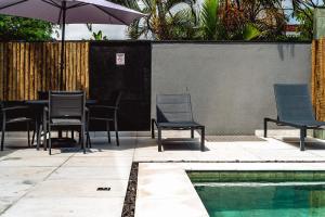 a patio with chairs and an umbrella next to a pool at JQY Beach Flats - 950m da Praia - Garagem subterrânea - Estação de carregamento para veículos elétricos in Juquei