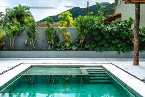 a swimming pool in front of a wall with plants at JQY Beach Flats - 950m da Praia - Garagem subterrânea - Estação de carregamento para veículos elétricos in Juquei