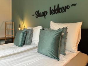 łóżko z zielonymi poduszkami i znakiem na ścianie w obiekcie Prachtige vakantievilla Burdaard w mieście Birdaard