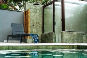 a swimming pool with a chair next to a house at JQY Beach Flats - 950m da Praia - Garagem subterrânea - Estação de carregamento para veículos elétricos in Juquei