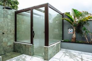 a glass shower in a building with a palm tree at JQY Beach Flats - 950m da Praia - Garagem subterrânea - Estação de carregamento para veículos elétricos in Juquei