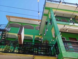 a green and white building with a balcony at Angel Wish Guesthouse in El Nido