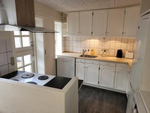 a kitchen with white cabinets and a stove in it at Skrædderens hus in Assens