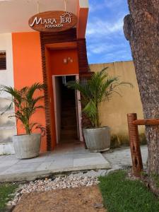 an entrance to a building with two plants in pots at Mara Jeri Pousada in Jericoacoara