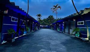 an empty street with blue buildings and palm trees at Cassino Motel 5 in Santo André