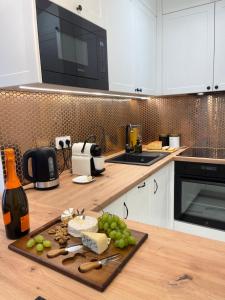 a kitchen with white cabinets and a cutting board with grapes at Apartament Komfort Promenada Ełk in Ełk