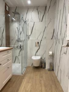 a bathroom with a toilet and a glass shower at Apartament Komfort Promenada Ełk in Ełk +16 photos