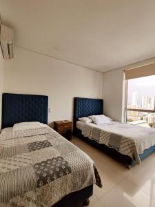 two beds in a room with a window at Palmetto Sunset Balcones con vista al mar Cartagena in Cartagena de Indias