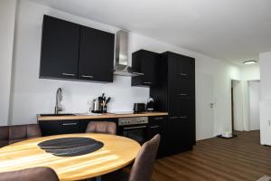 a kitchen with a wooden table and black cabinets at Waldblick am Ring in Kelberg