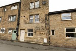 a brick building with a green door on a street at FORD GATE - Modern Luxury Cottage based in Holmfirth in Holmfirth