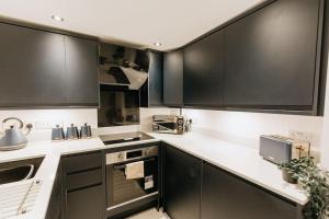 eine Küche mit schwarzen Schränken und weißen Arbeitsplatten in der Unterkunft FORD GATE - Modern Luxury Cottage based in Holmfirth in Holmfirth