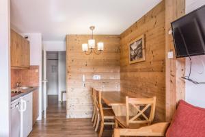 Il comprend une cuisine et une salle à manger avec un mur en bois. dans l'établissement Résidence Quartier Falaise - maeva Home - Studio 4 Personnes - Confort 69, à Avoriaz