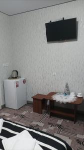 Zimmer mit einem Tisch und einem TV an der Wand in der Unterkunft Готель Ассоль in Chmelnyzkyj