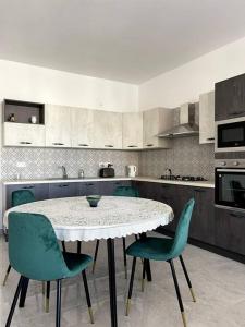 cocina con mesa blanca y sillas verdes en Apartment, Few Steps from Ghadira Bay, en Mellieħa