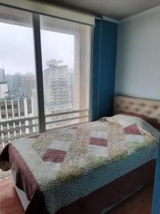 ein Schlafzimmer mit einer Decke auf einem Bett und einem Fenster in der Unterkunft Gran Santiago Apart in Santiago