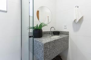a bathroom with a sink and a mirror at Pê na areia Loft Praia de Itaipú in Itaipu