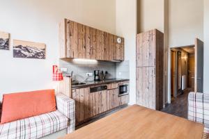 a kitchen with wooden cabinets and a couch in a room at Résidence Arietis - Atria-Crozats - maeva Home - Appartement 2 Pièces 5 Per 29 in Morzine
