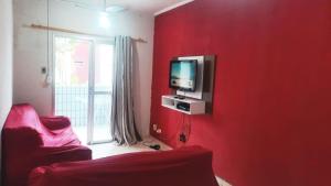 um quarto vermelho com uma televisão numa parede vermelha em Apartamento Praia Mongagua em Mongaguá