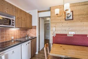 Una cocina con una mesa y un banco rojo. en Résidence Quartier Falaise - maeva Home - Studio 4 personnes Confort MAE-9083, en Avoriaz