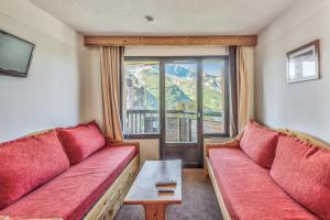una sala de estar con 2 sofás rojos y una ventana en Résidence Quartier Falaise - maeva Home - Studio 4 personnes Confort MAE-9083, en Avoriaz