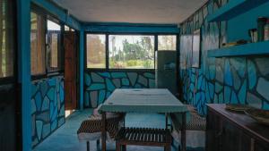 Piecefull bayview Cottage with Kitchen near Tofo في إنهامبان: غرفة زرقاء مع طاولة وبعض النوافذ